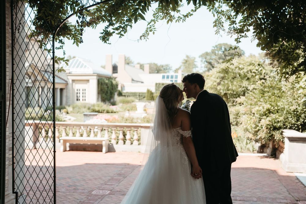 Bride and groom share a romantic kiss in silhouette framed by an elegant garden archway at their wedding venue.