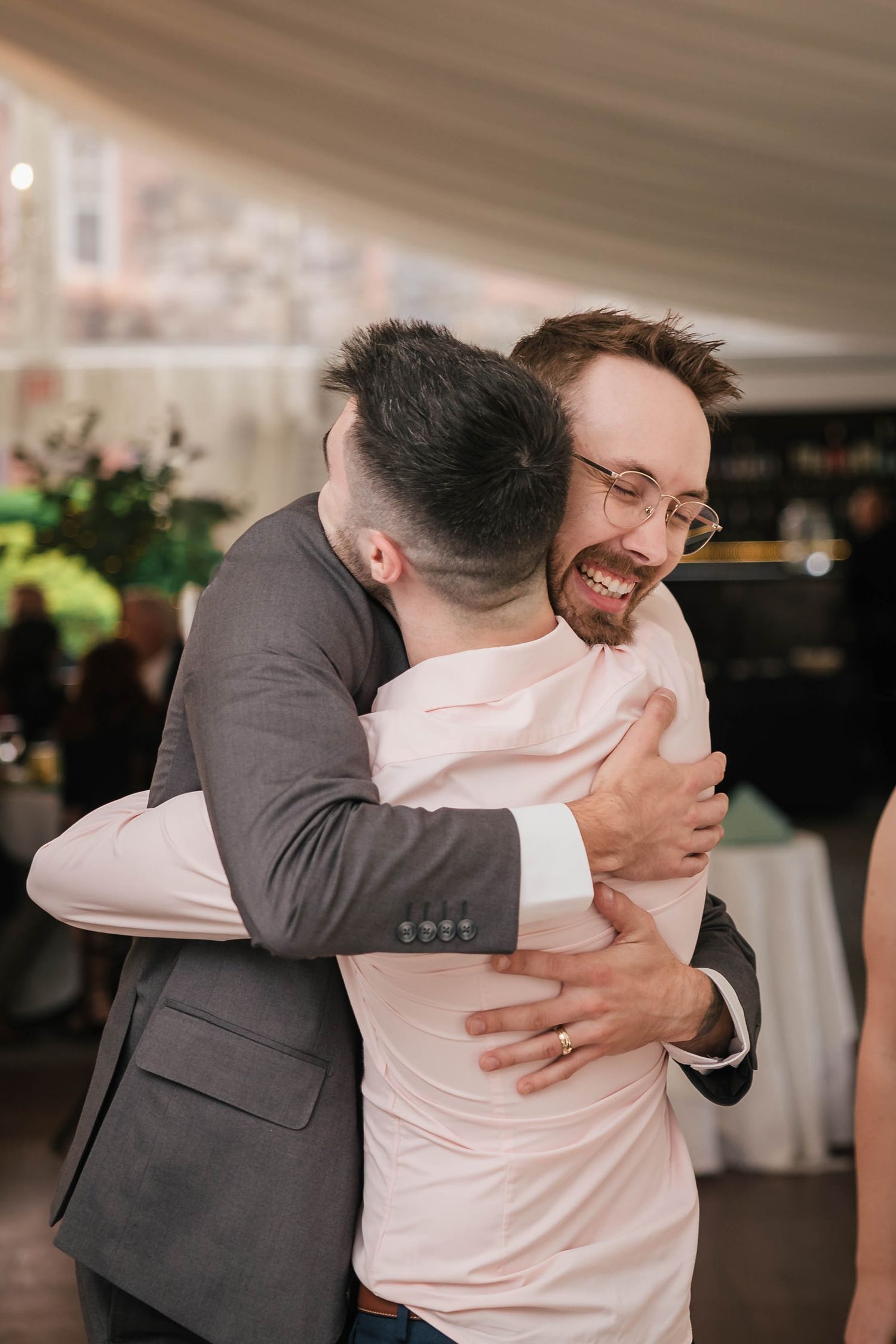 Groom laughing while hugging a guest tightly during the reception.