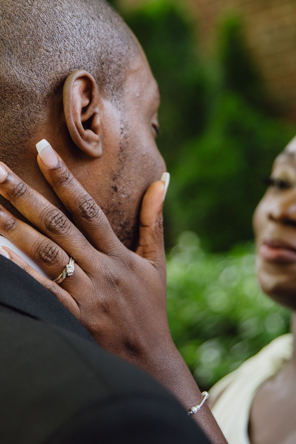 An emotional moment captured showing a groom's hand with wedding ring touching his face.