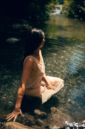Salt Lake City Utah Water Boudoir Photography by Carl James. Woman in river surrounded by green trees, posing in natural outdoor setting.