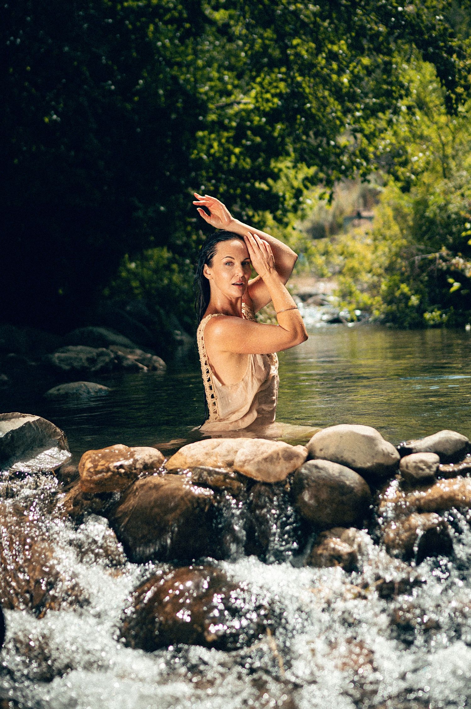 Salt Lake City Utah Water Boudoir Photography by Carl James. Woman in river surrounded by green trees, posing in natural outdoor setting.