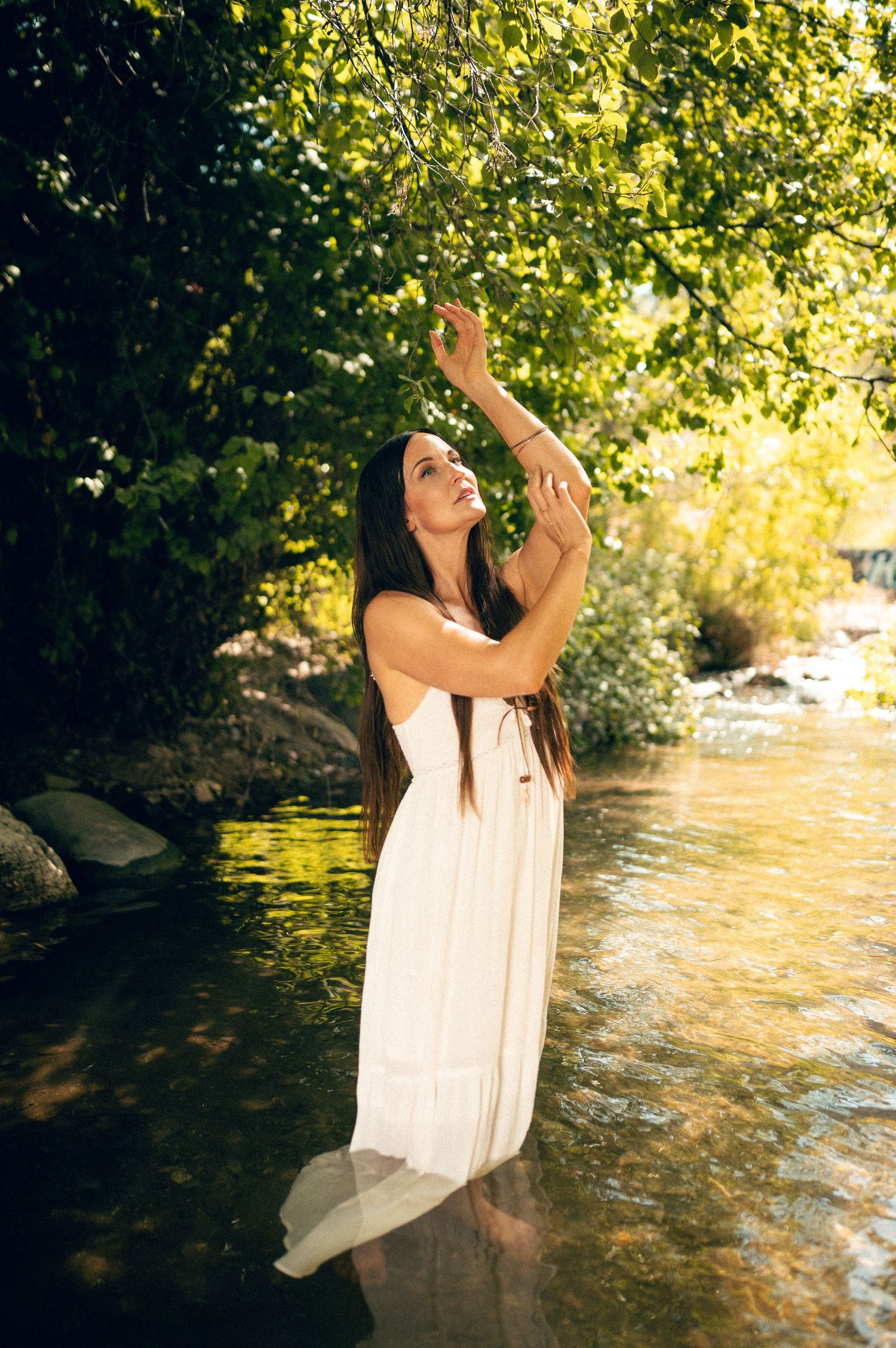 Salt Lake City Utah Water Boudoir Photography by Carl James. Woman in river surrounded by green trees, posing in natural outdoor setting.