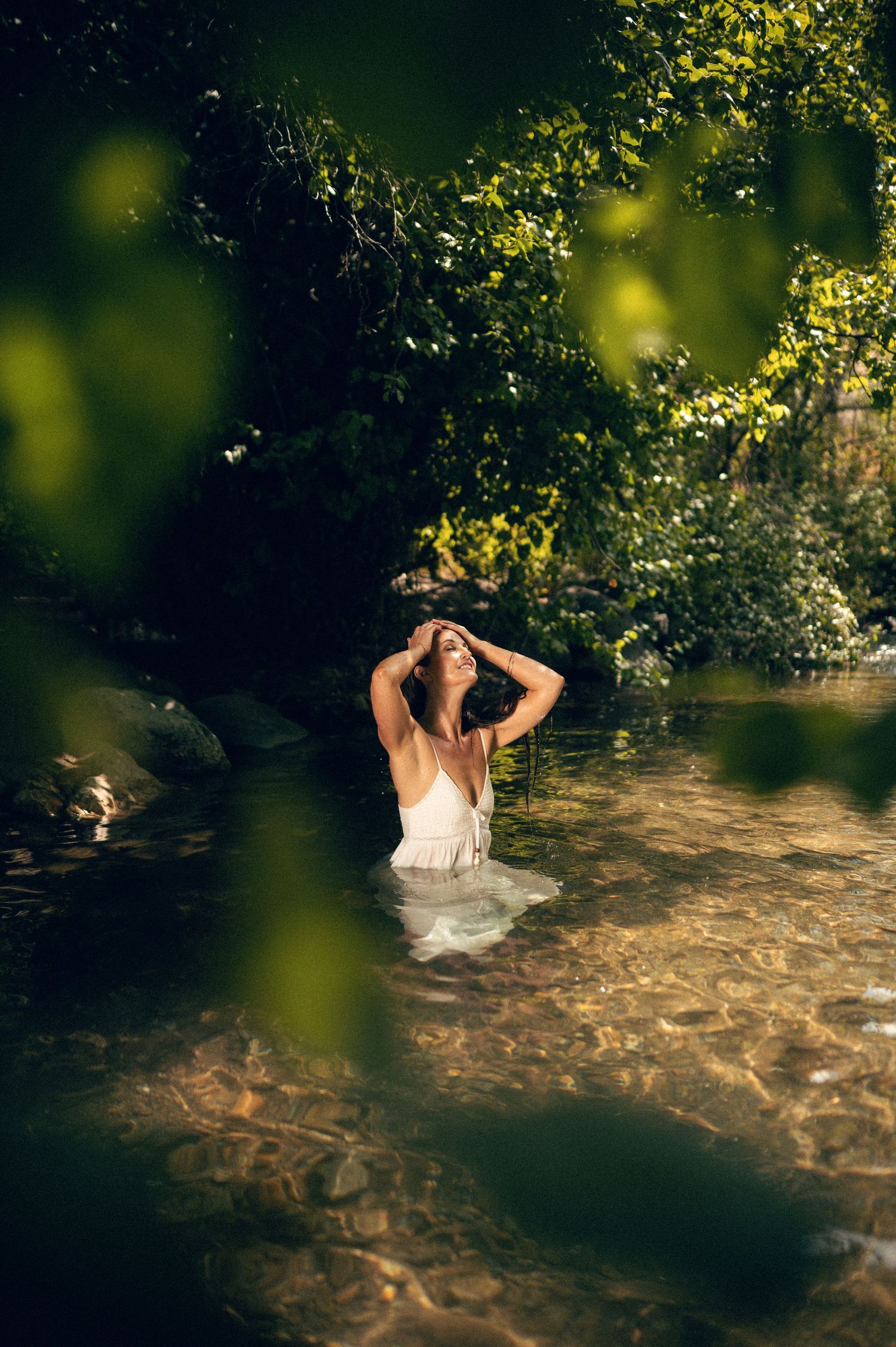 Salt Lake City Utah Water Boudoir Photography by Carl James. Woman in river surrounded by green trees, posing in natural outdoor setting.