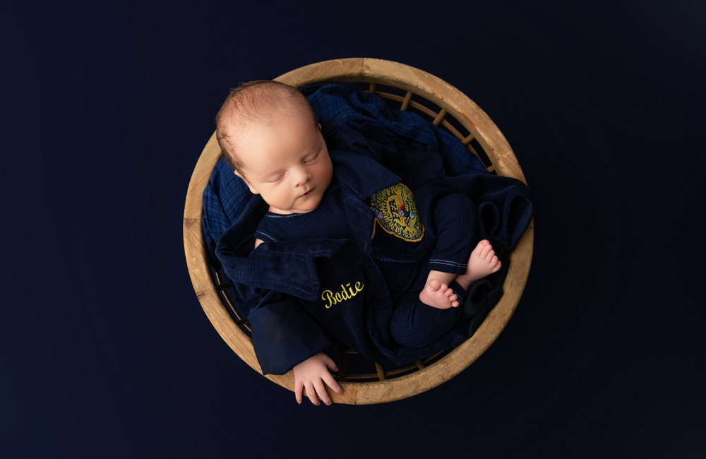 Sleeping newborn baby boy wearing a FFA jacket during a studio newborn session