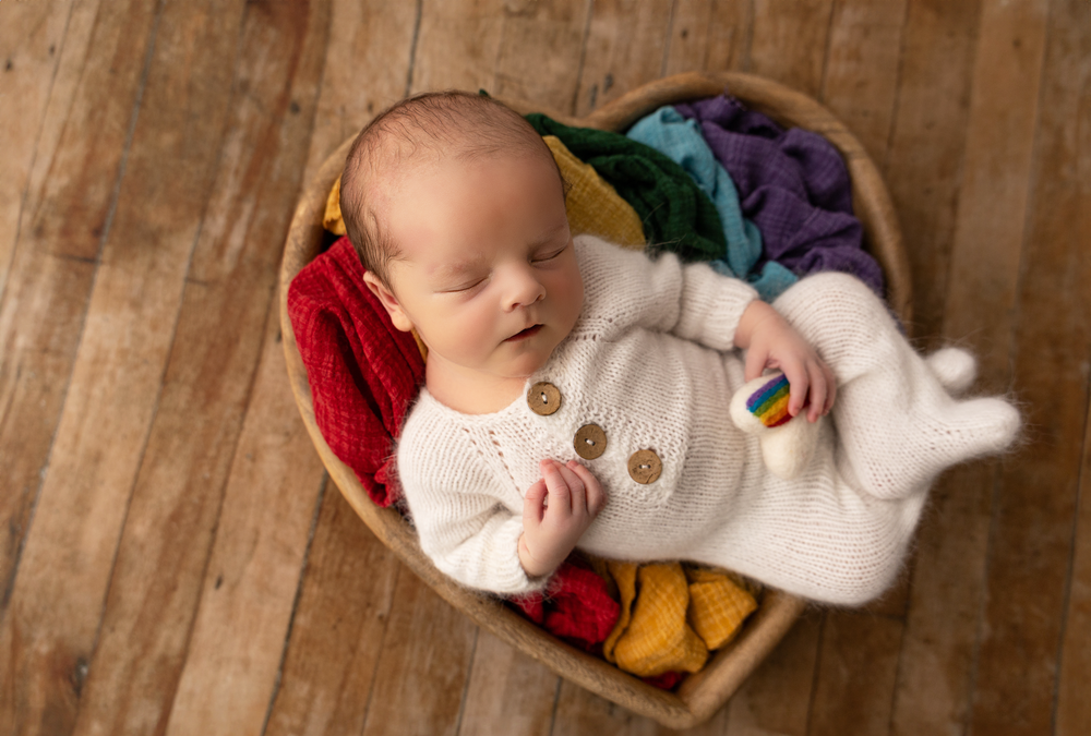Posed newborn baby boy photographed in a rainbow baby themed setup