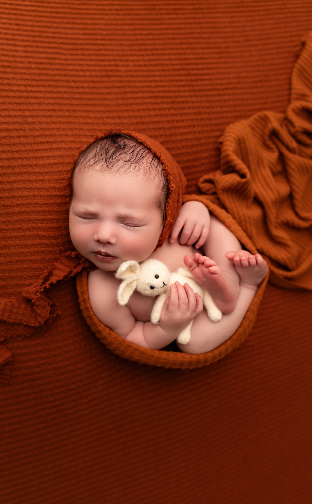 Posed newborn baby boy photographed in a orange fall custom setup