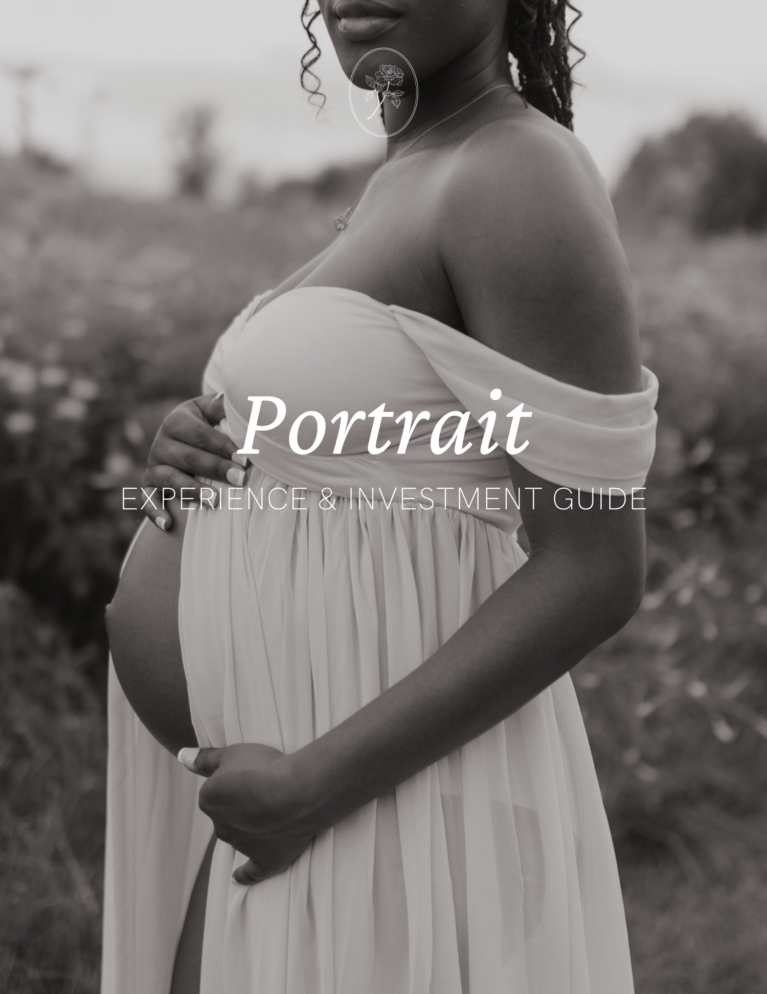 Black and white portrait of a pregnant woman in a flowing white off-shoulder gown standing in a field.