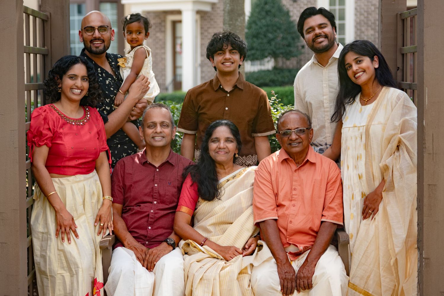 Multi-generational Indian family posing together outdoors in traditional and festive attire.