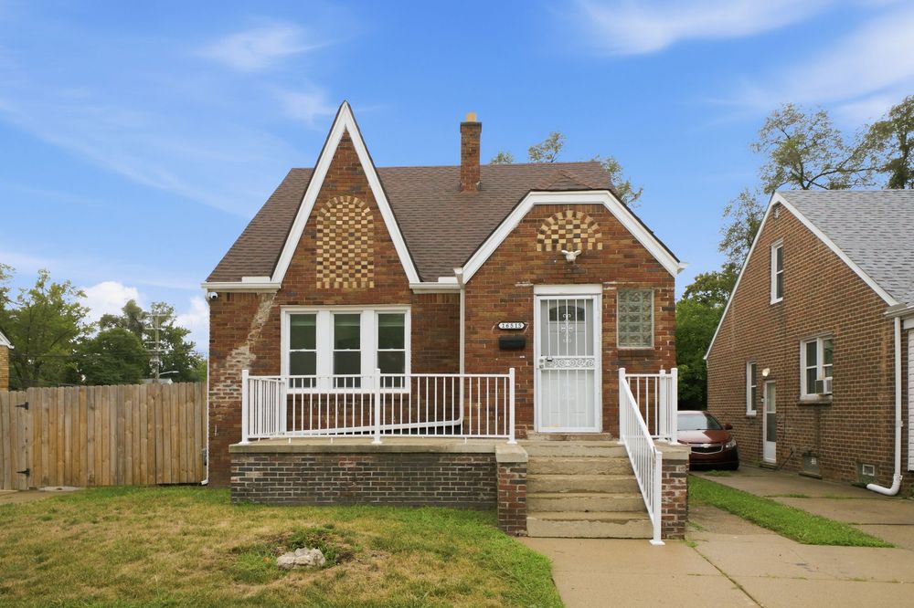 Charming brick bungalow with white trim, decorative gable, covered porch, and lush green lawn in a residential neighborhood.