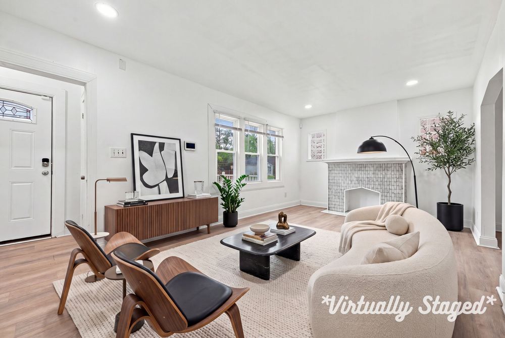 Virtually staged bright living room with modern furniture, fireplace, hardwood floors, and large windows in a white interior.