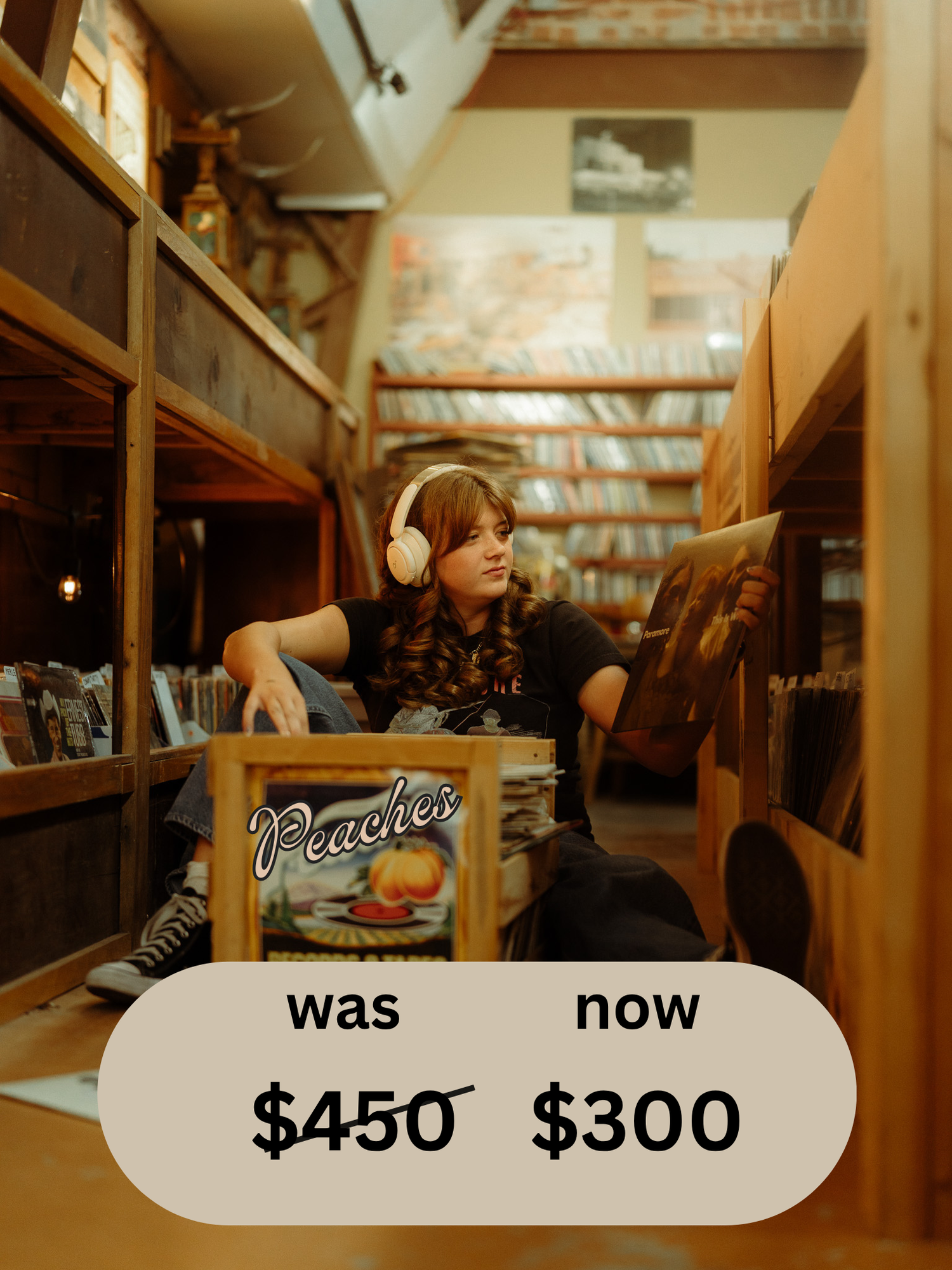 Person with headphones sitting on floor browsing vinyl records at Peaches Records and Tapes store.