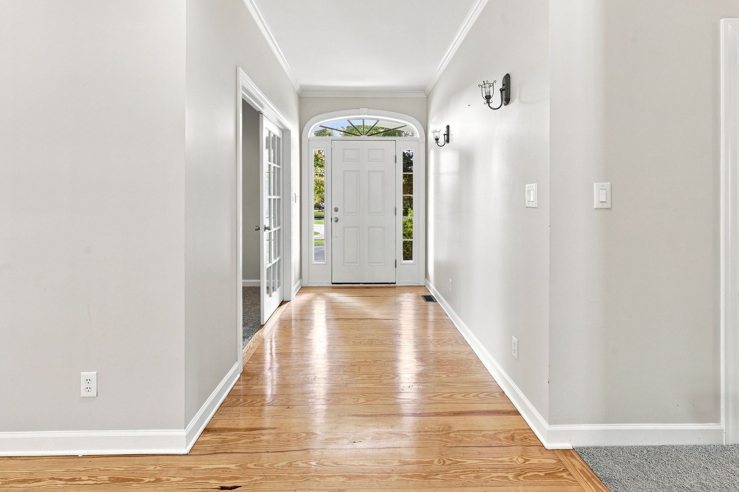 Bright home entryway looking directly into an open-concept living area with polished hardwood flooring for a Real Estate Listing in Bath, NC