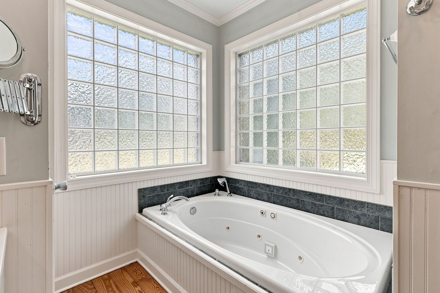 Modern primary bathroom with a tub and polished wood floor, highlighting clean fixtures for a property listing.