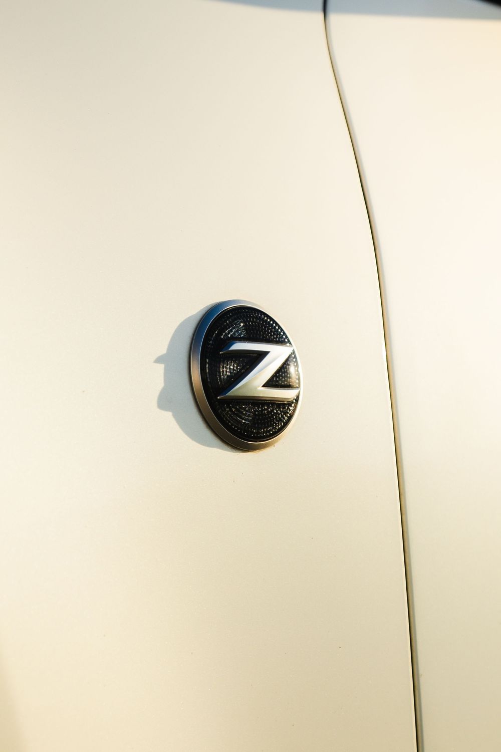 Close-up of Nissan Z emblem badge on white car body panel.