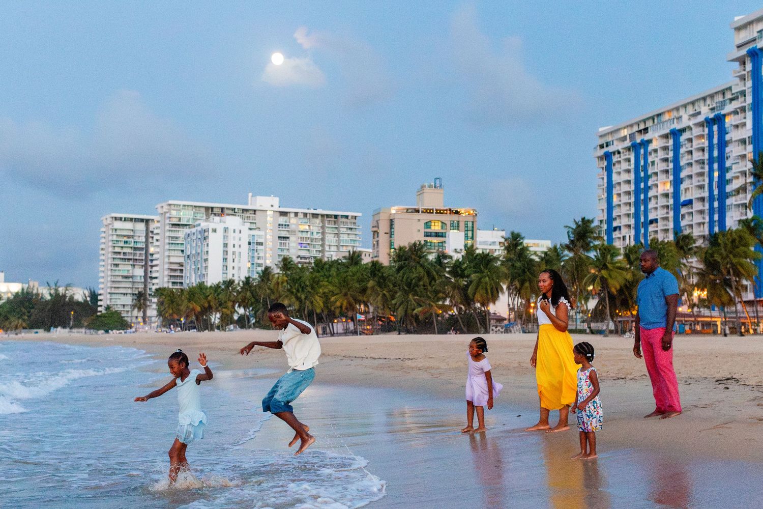 Family portrait. Mom, dad, and four kids on the beach with the moon in the background in Isla Verde, Carolina, Puerto Rico.