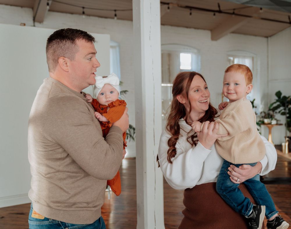 Young family with two babies sharing a joyful moment indoors.