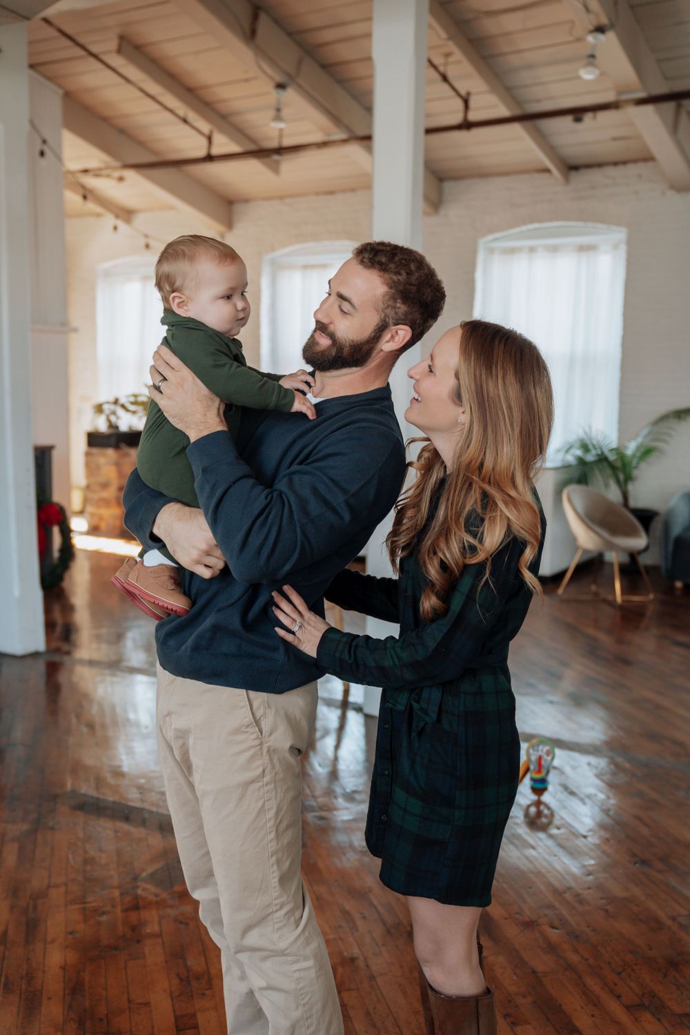 Young family of three sharing a tender moment in a bright loft.