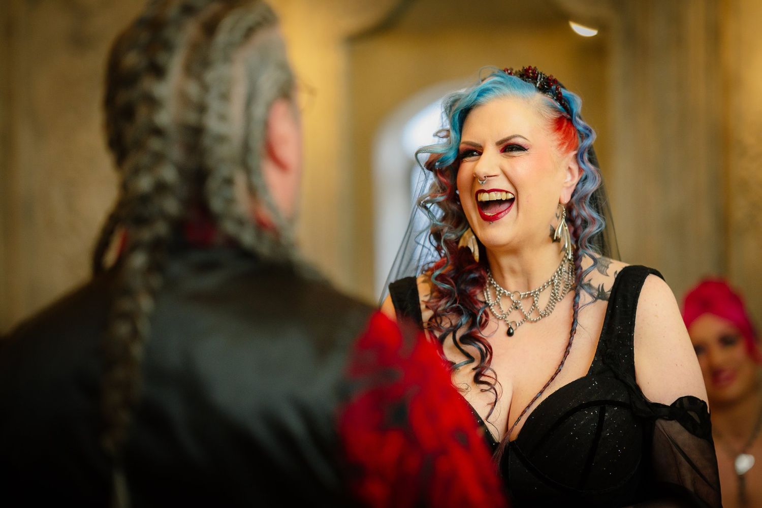 Bride with blue and red hair laughing during the wedding vows in the Le Petit Chateau ceremony room