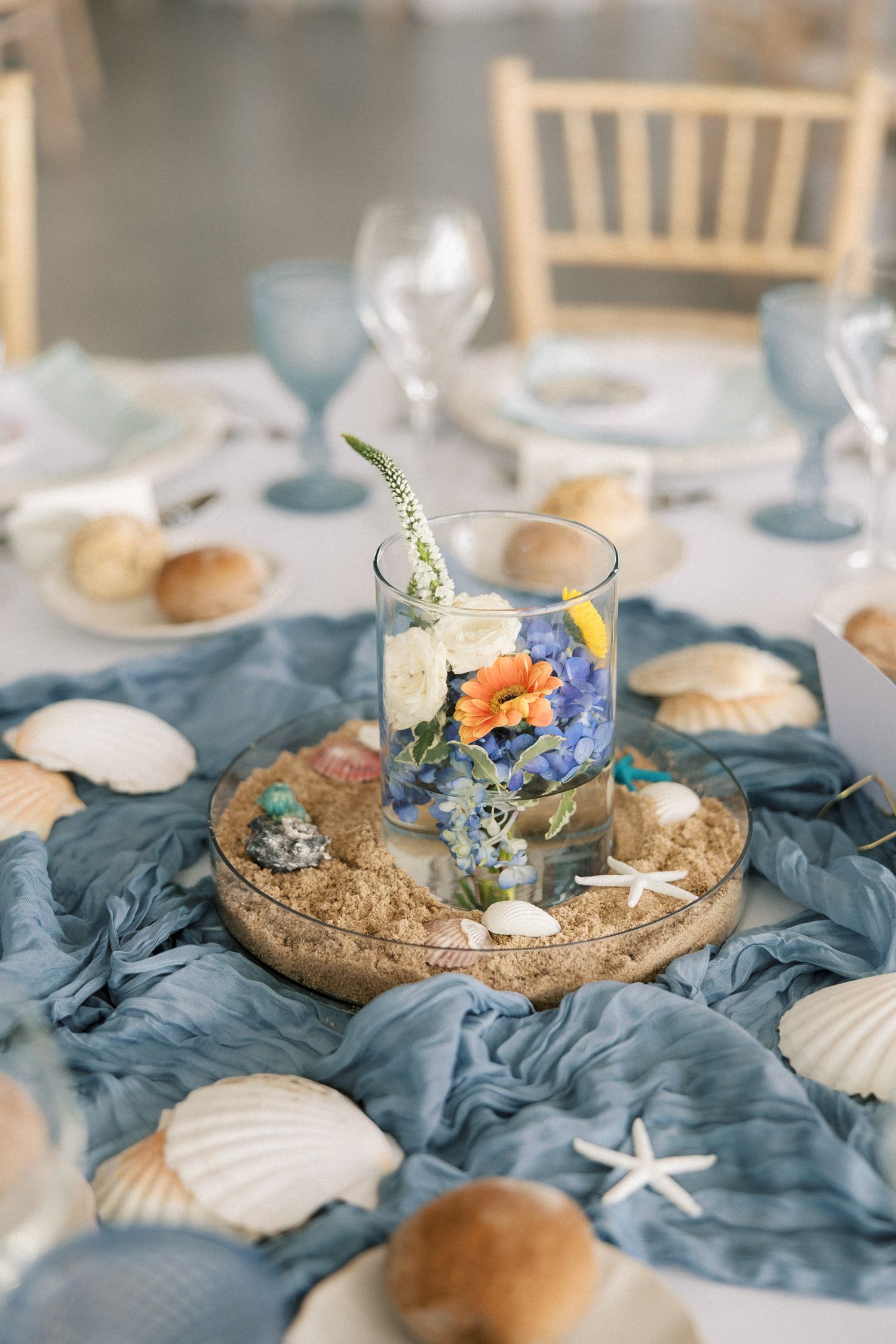 Elegant coastal wedding reception decor featuring blue linens, seashells and fresh flowers at Arriba by the Sea.