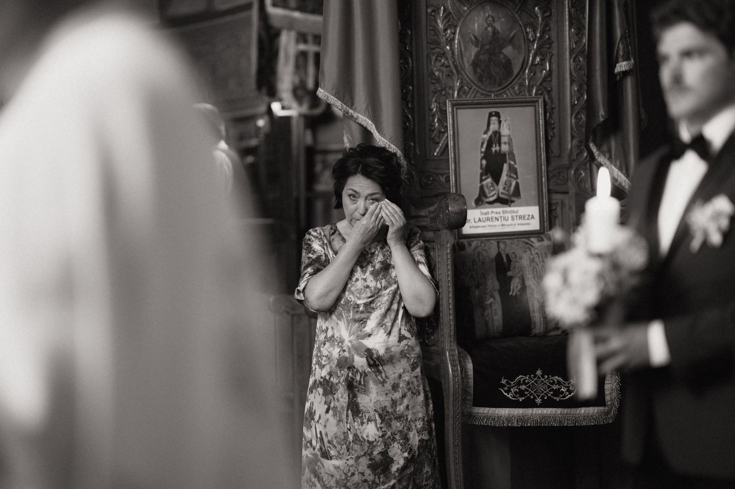 Black and white photo of emotional woman covering mouth during wedding ceremony in church.