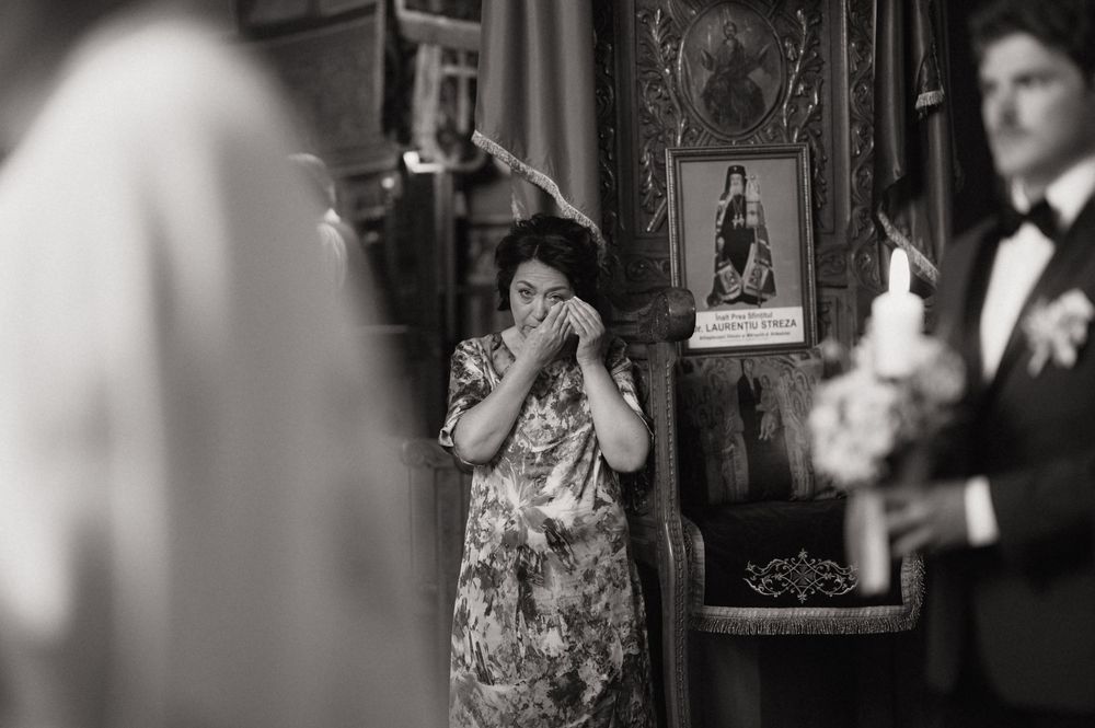 Black and white photo of emotional woman covering mouth during wedding ceremony in church.