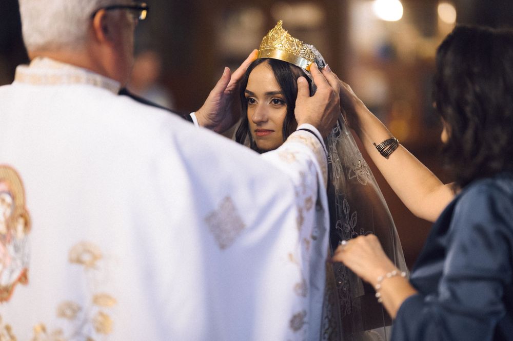 Priest placing a golden crown on a bride during an Orthodox wedding ceremony.