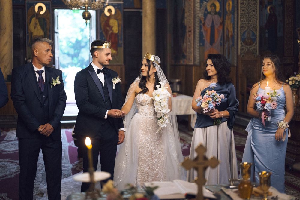 Bride and groom stand at church altar with wedding party during orthodox ceremony.