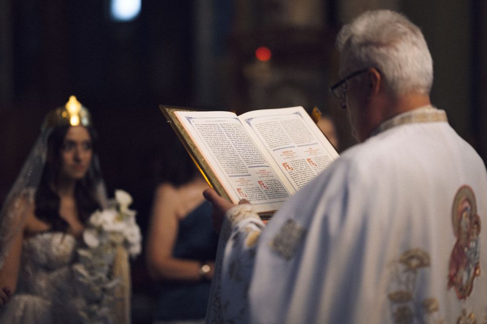 Priest reading from a religious book during a traditional church wedding ceremony with a bride in a veil.