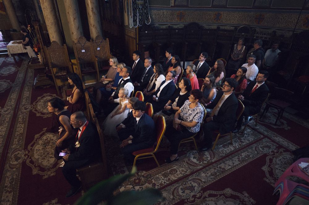 Aerial view of elegantly dressed guests seated in ornate chairs at a formal indoor ceremony or event.
