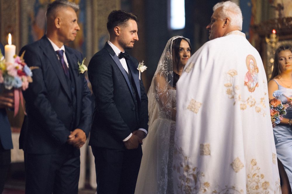 A couple exchanges vows in a traditional church wedding ceremony, officiated by a priest in ornate robes.