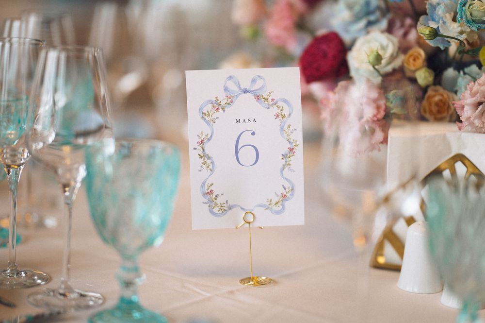 Elegant wedding table setting with a floral table number 6 card, teal goblets, and colorful floral centerpiece.