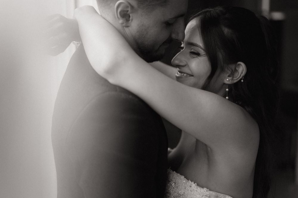 Black and white close-up of a smiling bride embracing her groom on their wedding day.