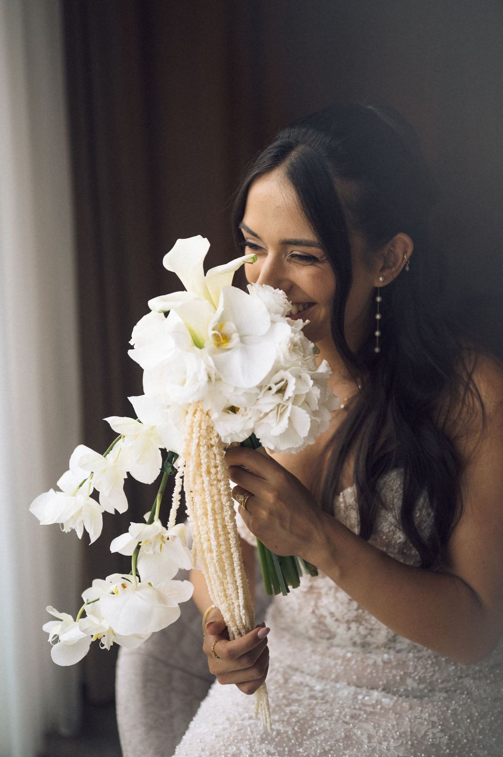 Smiling bride holding a bouquet of white calla lilies and orchids on her wedding day.