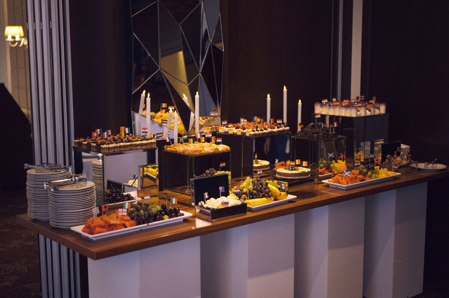 Elegant buffet table with gourmet food displays, candles, and decorative arrangements at an upscale catered event.