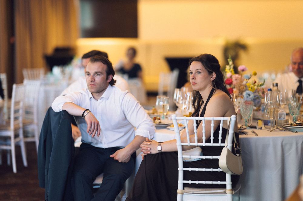 Man and woman sitting at elegantly decorated wedding reception table, looking thoughtfully into the distance.