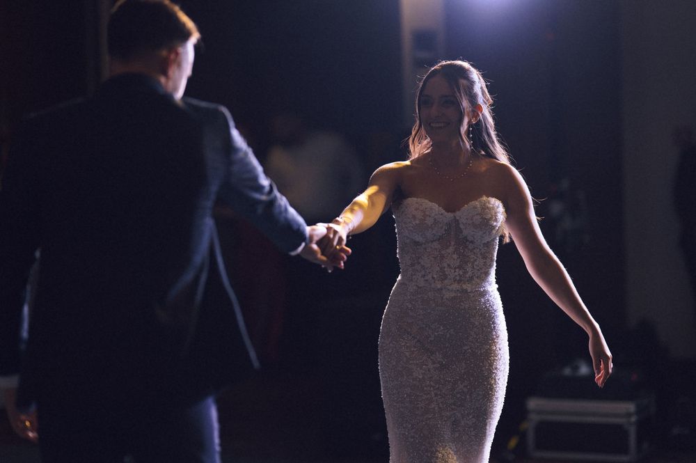 Bride in a beaded strapless gown shares a first dance with her partner at a romantic wedding reception.