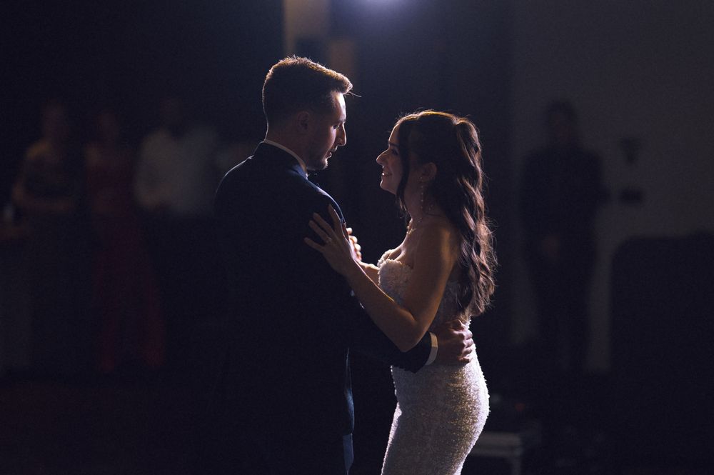 Couple sharing their first dance at a wedding reception in a dimly lit venue.