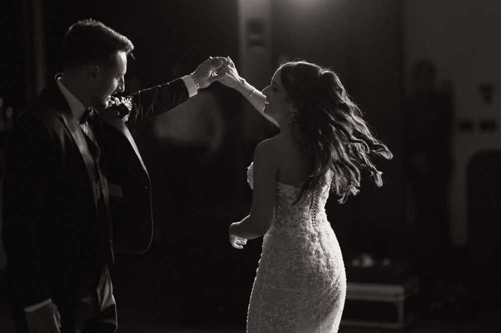Black and white photo of a bride and groom sharing their first dance at a wedding reception.