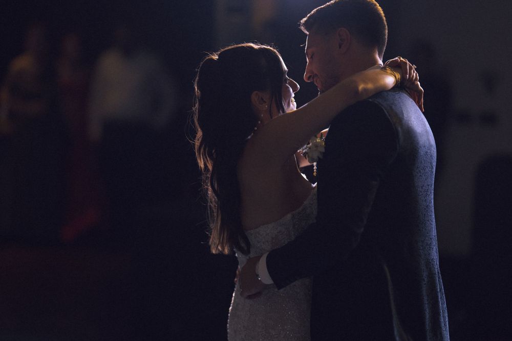 Couple sharing a romantic first dance in dim lighting at a wedding reception.
