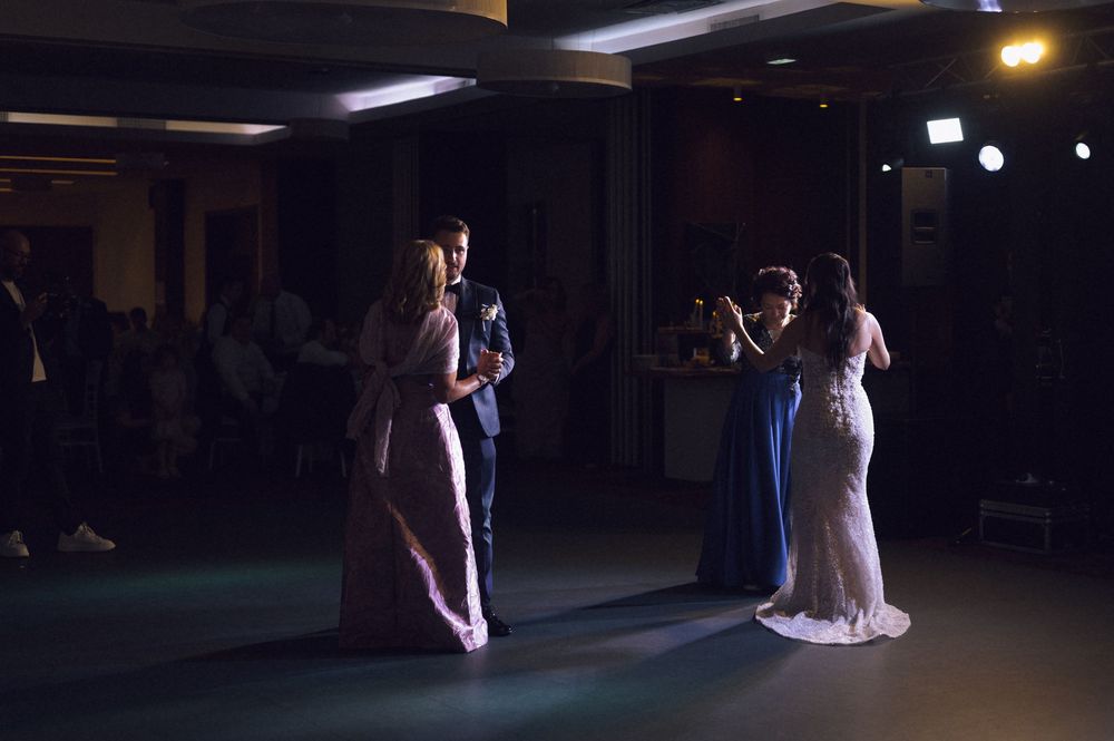 Elegant wedding reception with guests in formal attire dancing in a dimly lit ballroom venue.