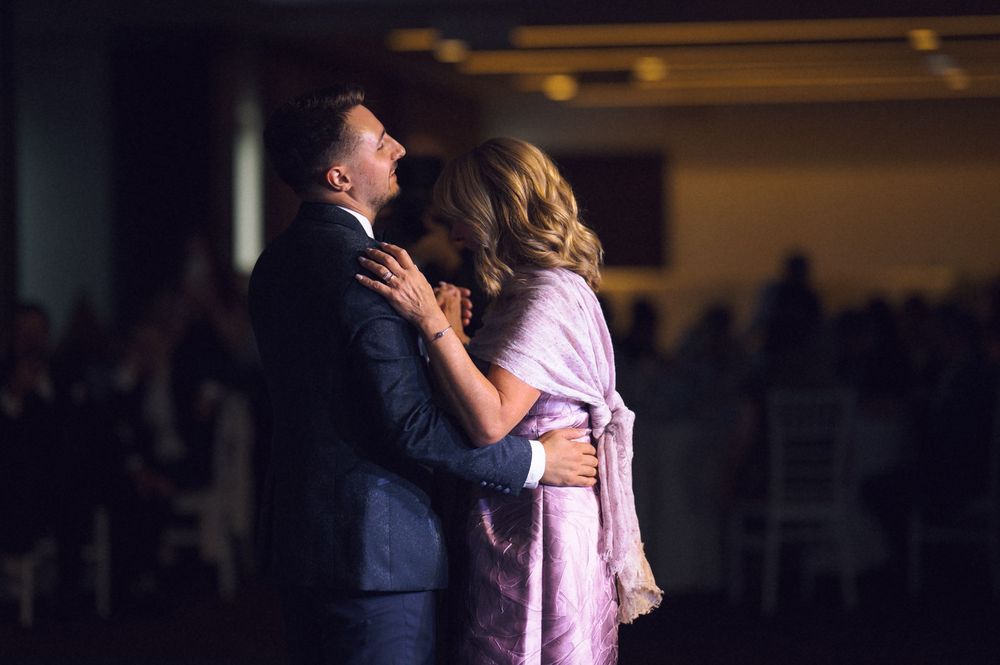 Couple sharing an intimate dance embrace at a formal evening event in a dimly lit banquet hall.