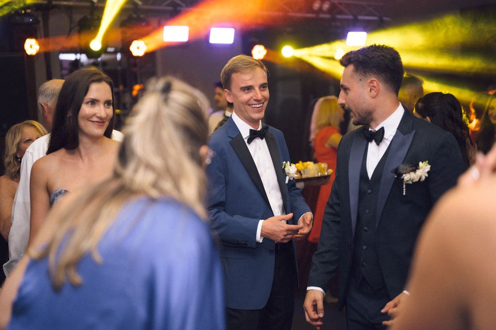 Elegantly dressed guests in formal attire socializing at an upscale evening event or gala celebration.