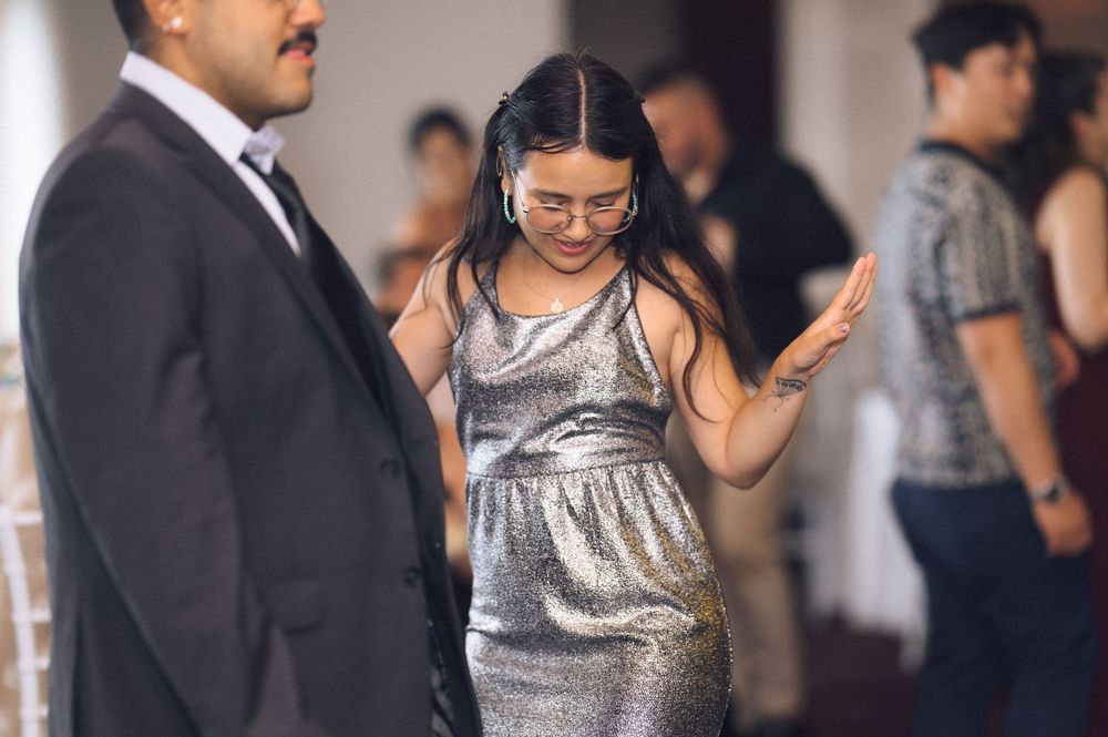 Woman in silver sequin dress wearing glasses at a formal event, looking down gracefully.