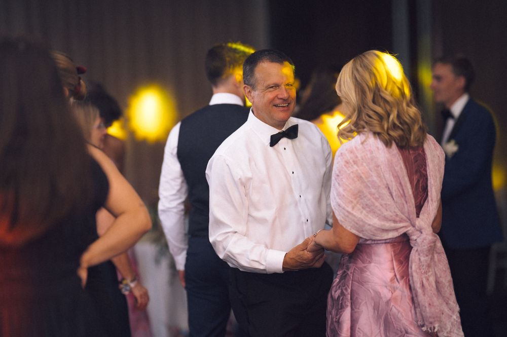 Elegantly dressed couple dancing and smiling at a formal event, man in tuxedo with bow tie.