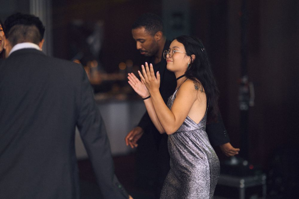 A woman in a silver dress dances with a man in a suit at an elegant evening event.