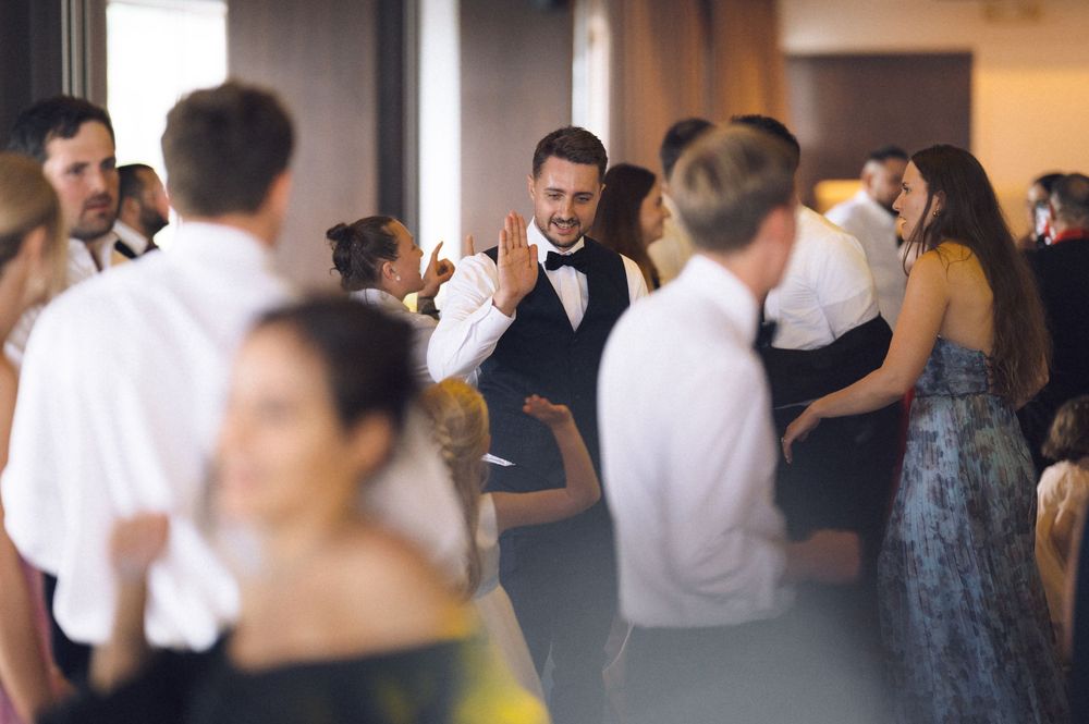 Guests dancing and socializing at an elegant wedding reception in a bright venue.