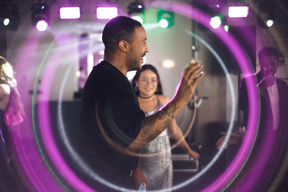 People dancing at a vibrant nightclub party with colorful purple neon lights and laser effects.
