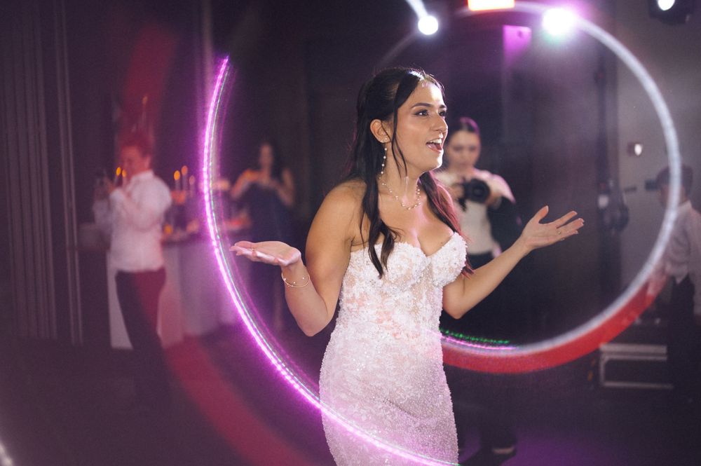 Woman in white lace dress dancing at elegant event with glowing pink and red light rings.