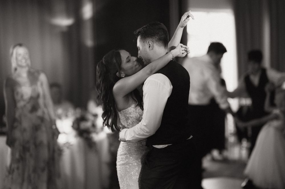 Black and white photo of a bride and groom sharing their first dance at a wedding reception.
