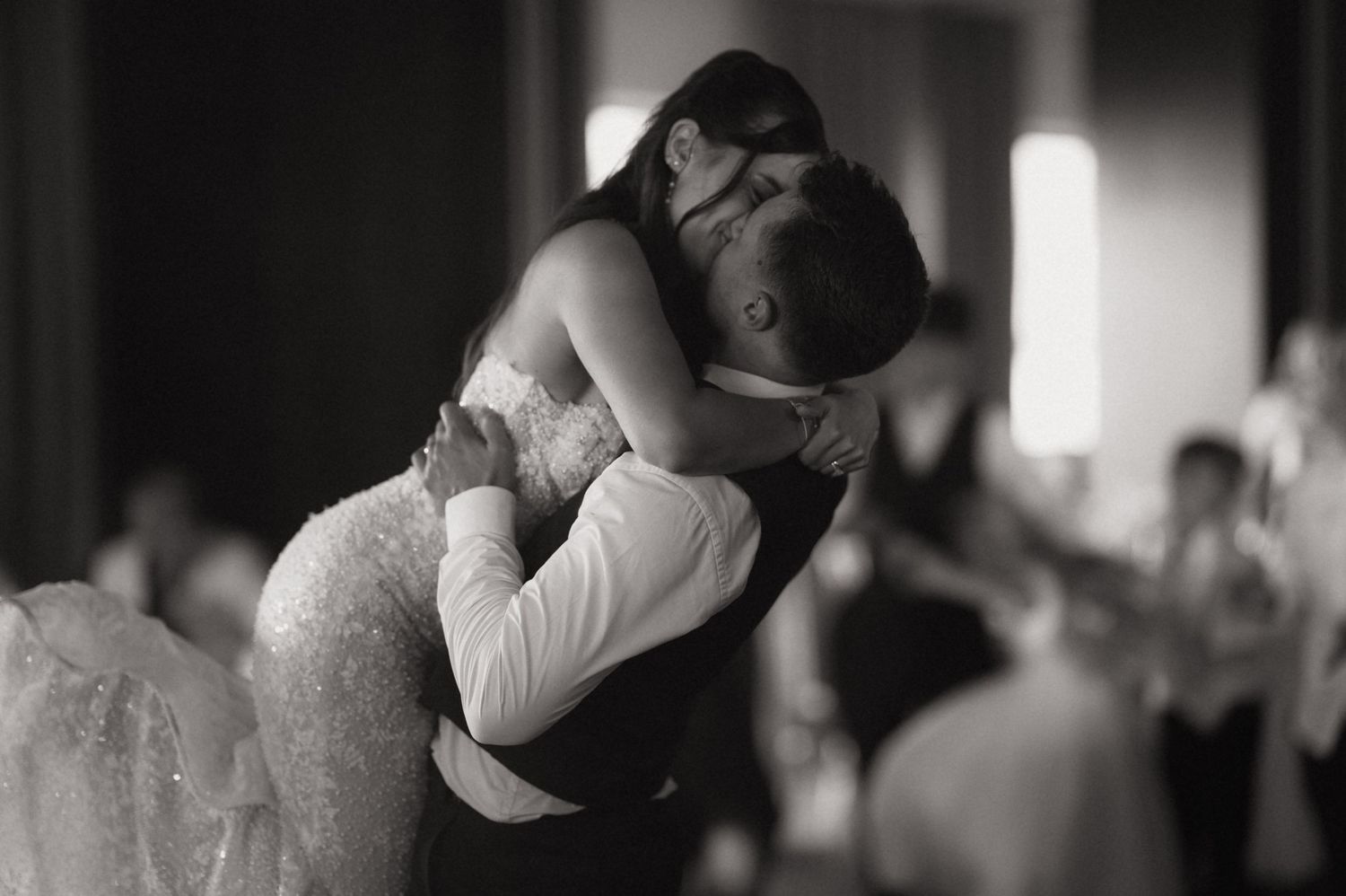 Black and white photo of bride and groom sharing romantic first dance embrace at wedding reception.